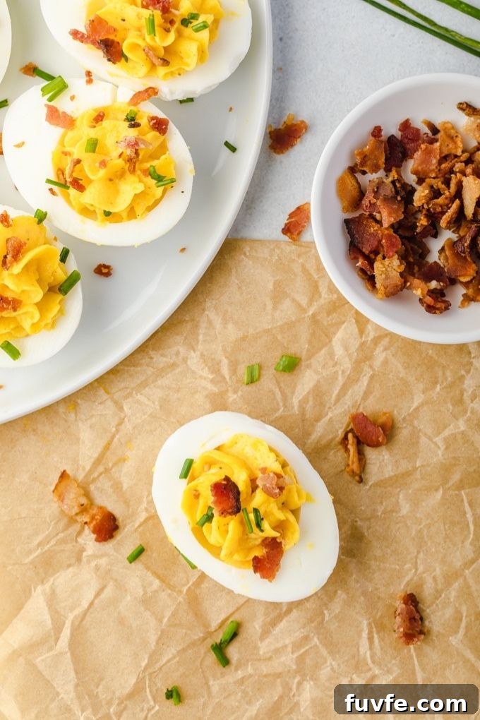 Bacon deviled eggs on a plate with bowl of bacon
