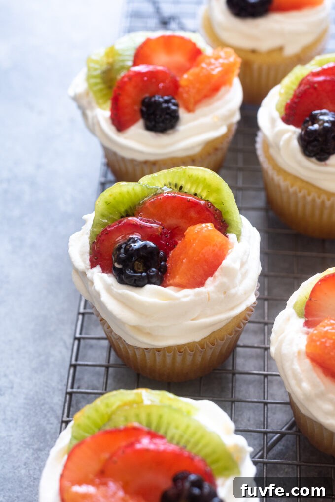 Vanilla cupcakes with fruit on top.