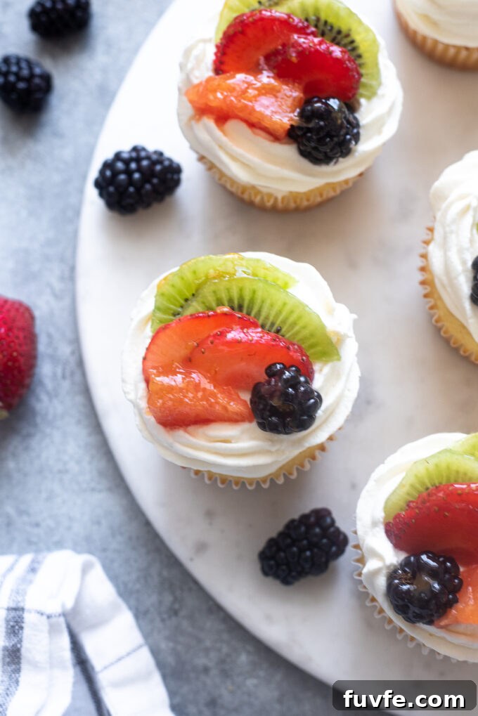 Vanilla cupcakes topped with whipped cream and fresh fruit.