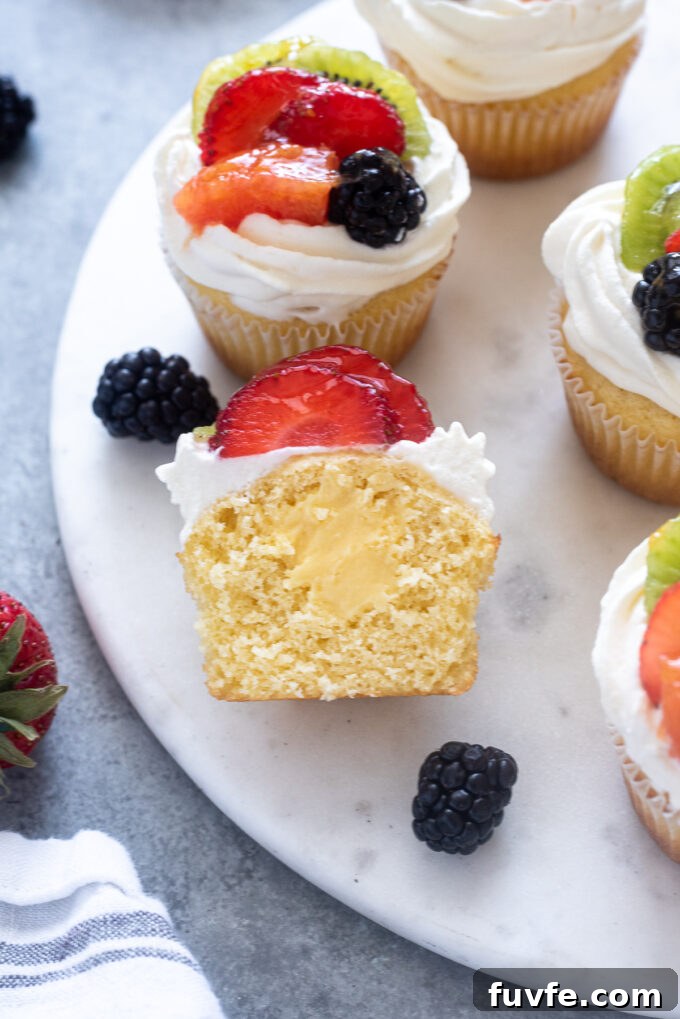 Fruit tart vanilla cupcake cut in half to display pastry cream filling.
