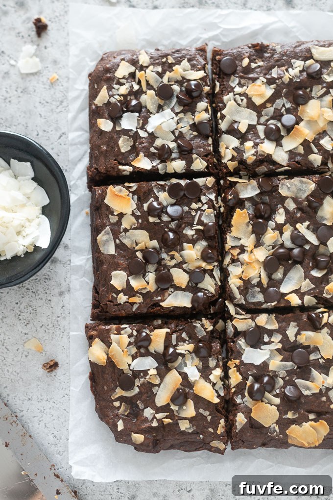 Coconut brownies cut into squares on parchment