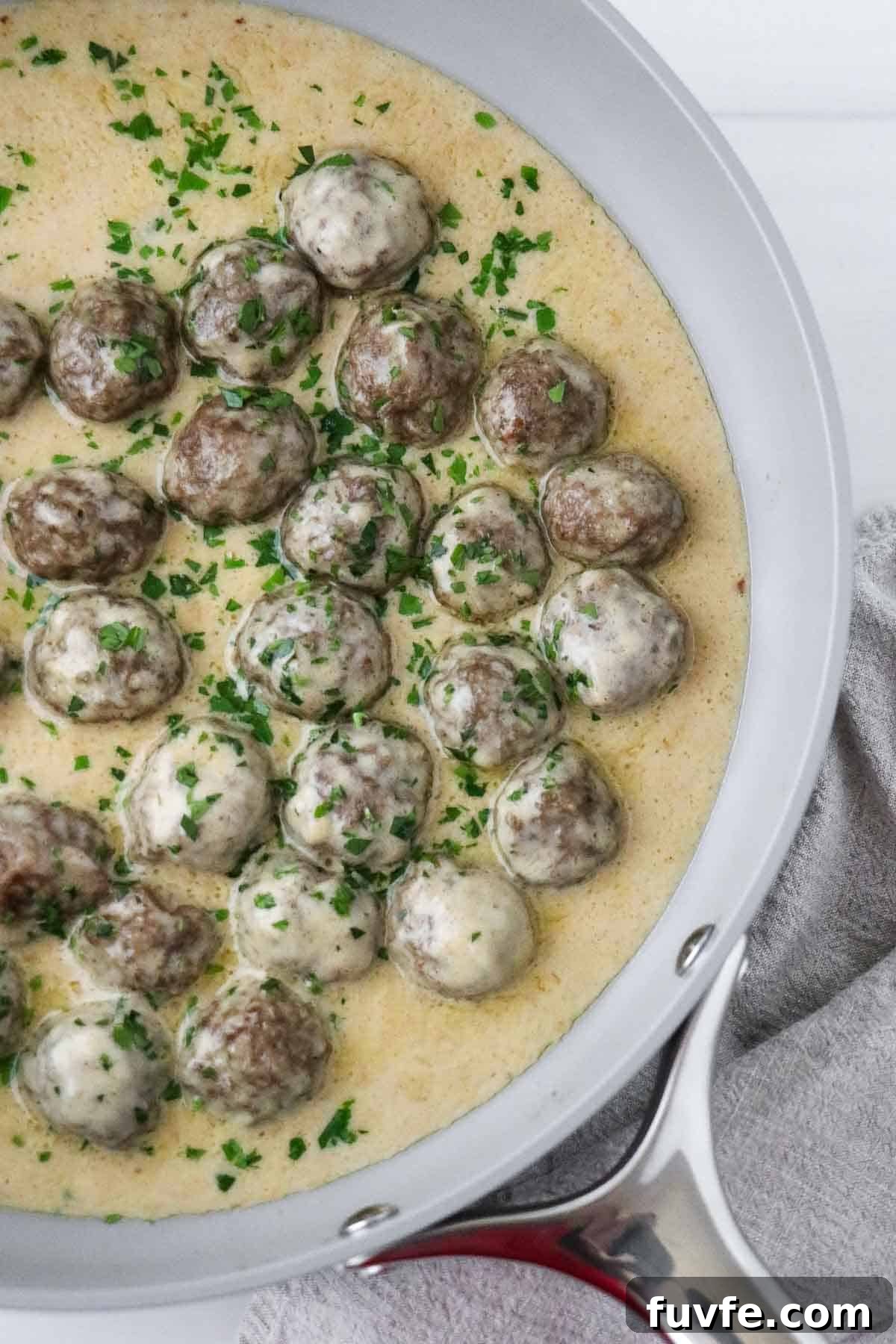 Swedish Meatballs with Classic Creamy Gravy (Köttbullar) 2 Swedish Meatballs with Gravy in a skillet sprinkled with parsley.