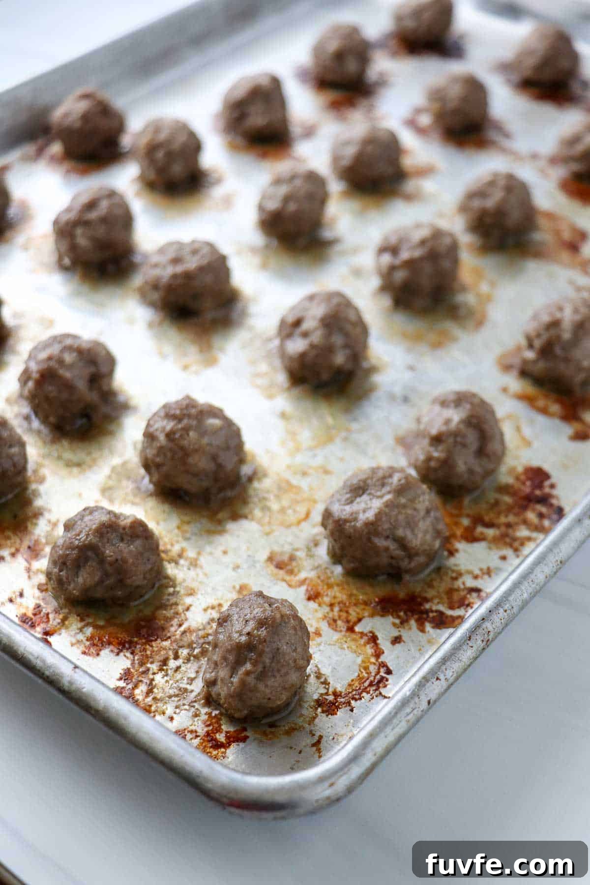 Swedish Meatballs with Classic Creamy Gravy (Köttbullar) 11 Cooked Swedish Meatballs on a baking sheet.