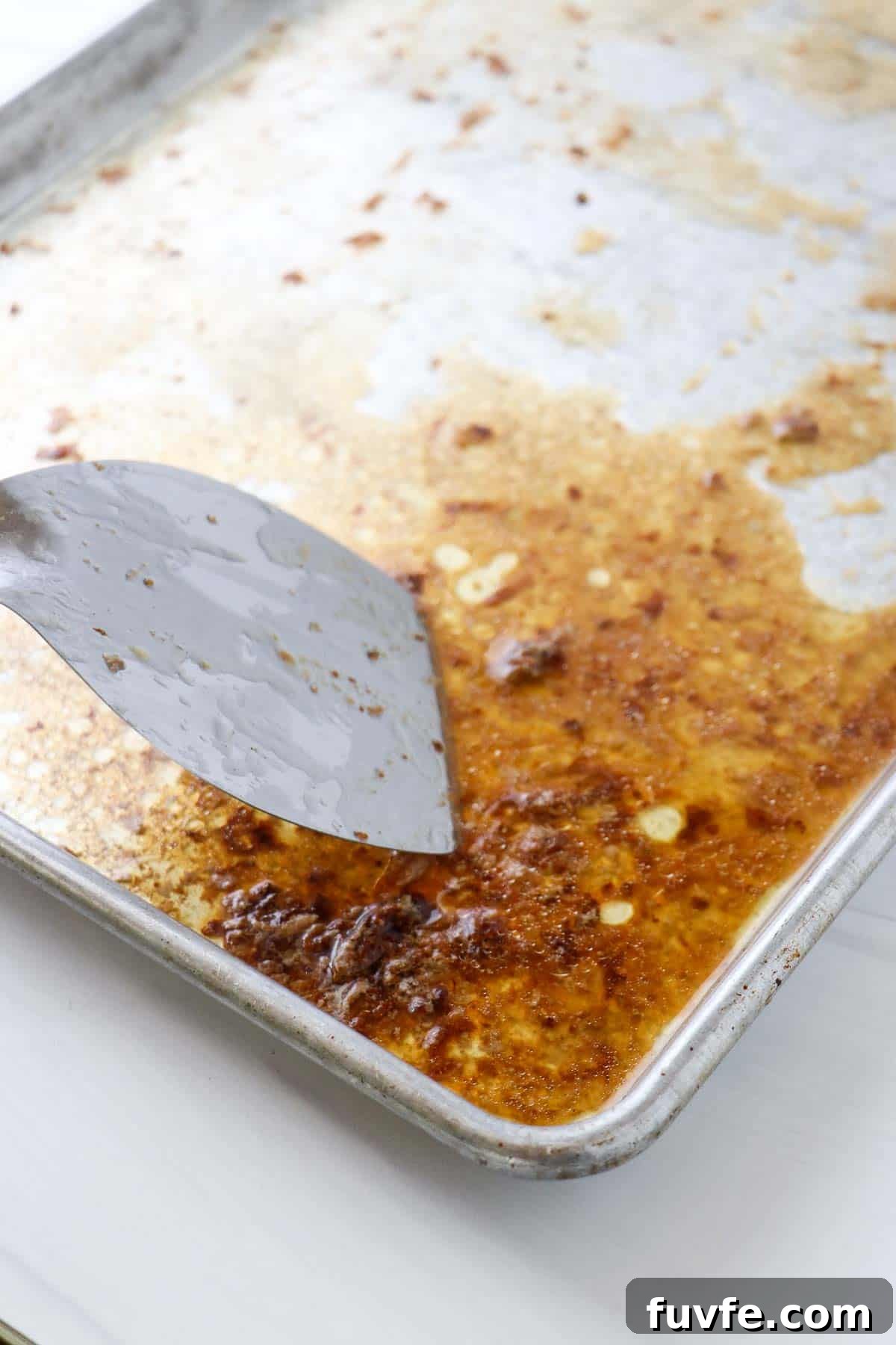 Swedish Meatballs with Classic Creamy Gravy (Köttbullar) 12 Baking sheet with brown bits and a metal spatula.