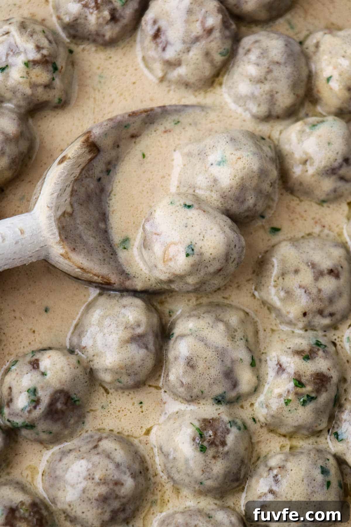 Swedish Meatballs with Classic Creamy Gravy (Köttbullar) 13 Close up of Swedish Meatballs with Gravy and a wooden spoon.