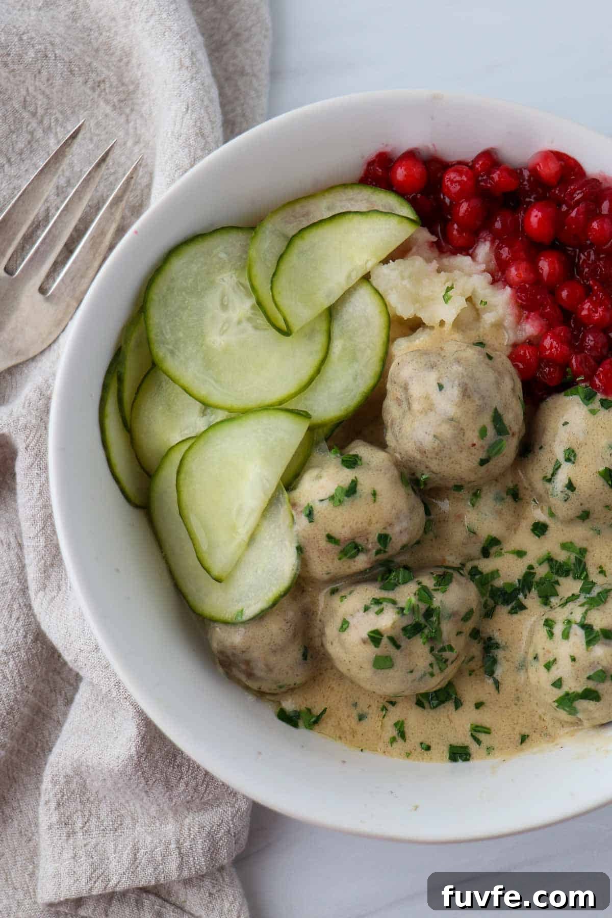 Swedish Meatballs with Classic Creamy Gravy (Köttbullar) 14 Overhead shot of Swedish Meatballs with Gravy and pickles and lingonberries.