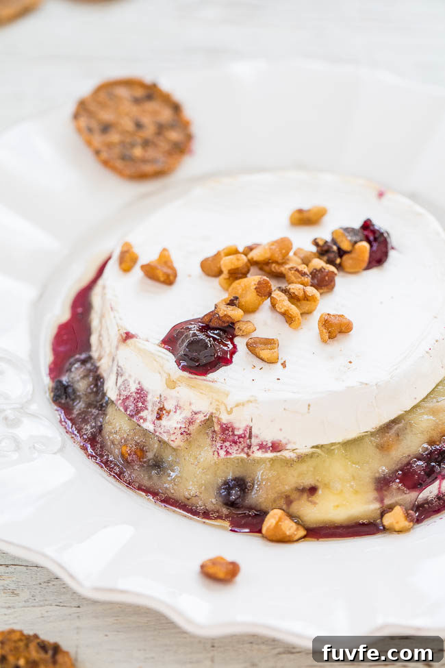 Black currant and walnut stuffed baked brie on a plate. 