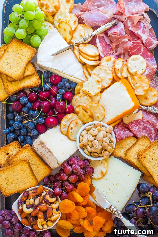 A meat and cheese board with grapes, cherries, blueberries, toast pieces, and crackers. 
