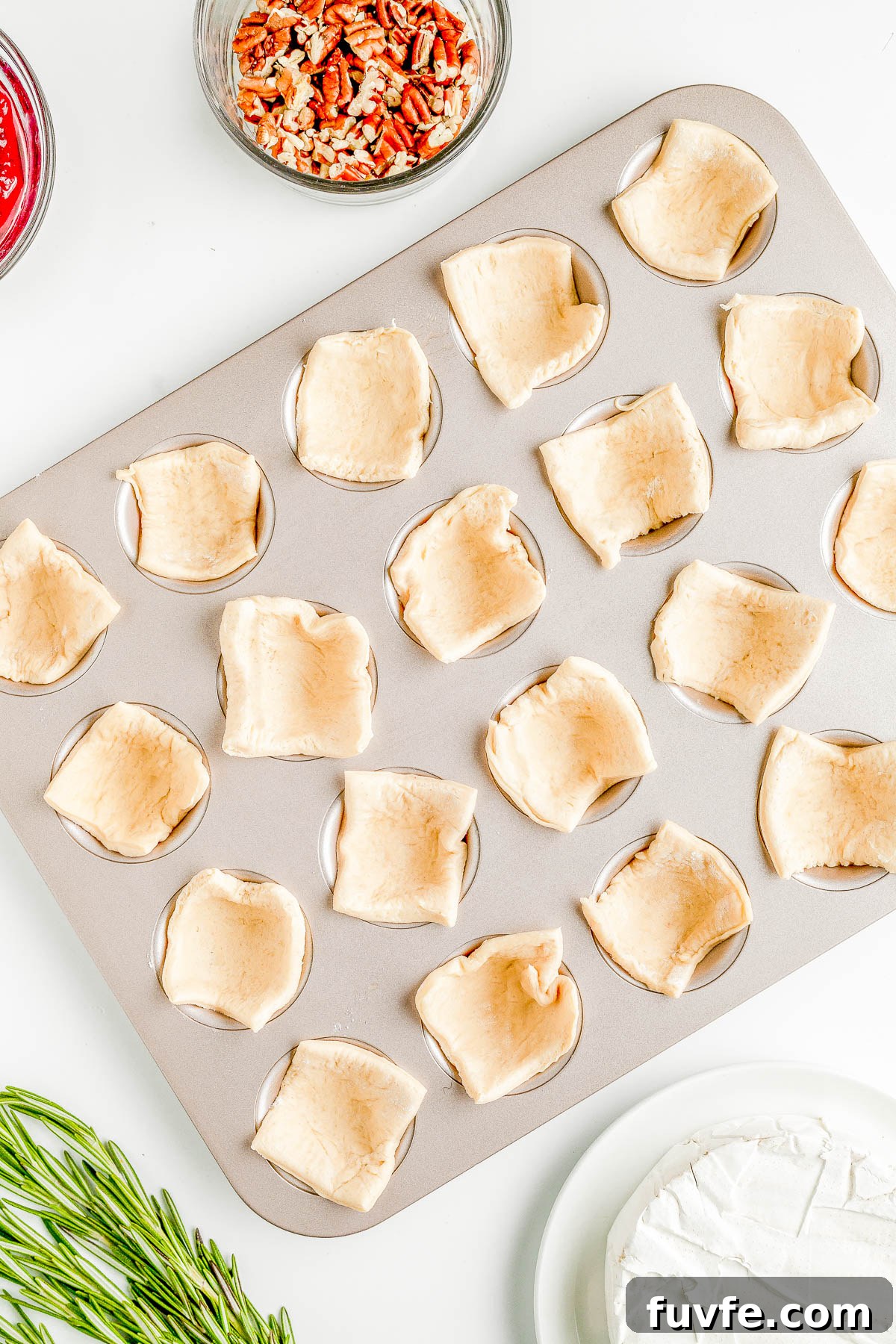 A muffin tin filled with raw crescent roll dough in the cavities. 
