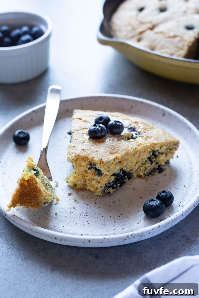 Slice of blueberry cornbread on plate with a fork