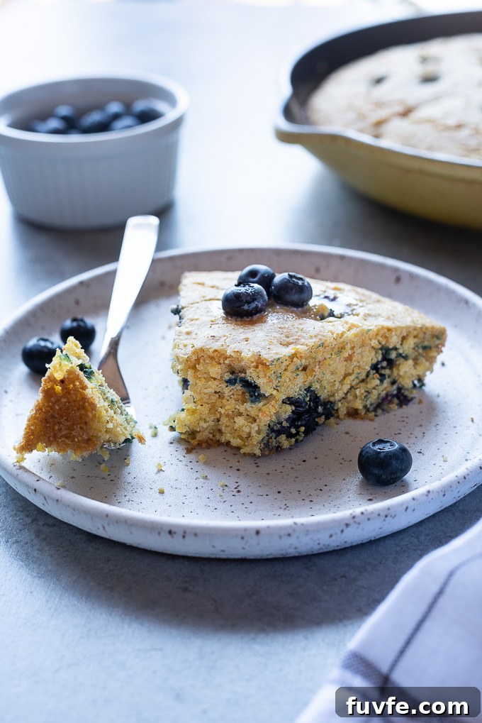 Wedge of blueberry cornbread on a plate with bite missing