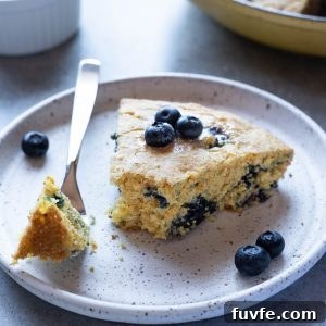 Slice of blueberry cornbread on plate with a fork