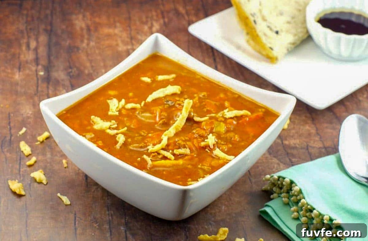 Award-Winning Shredded Carrot Chowder Recipe 2 creamy carrot soup in a white bowl with bread on a plate in the background