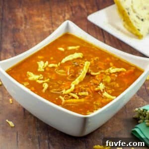 Award-Winning Shredded Carrot Chowder Recipe 11 Carrot Tomato Soup in white bowl on brown wooden surface, with bread in background