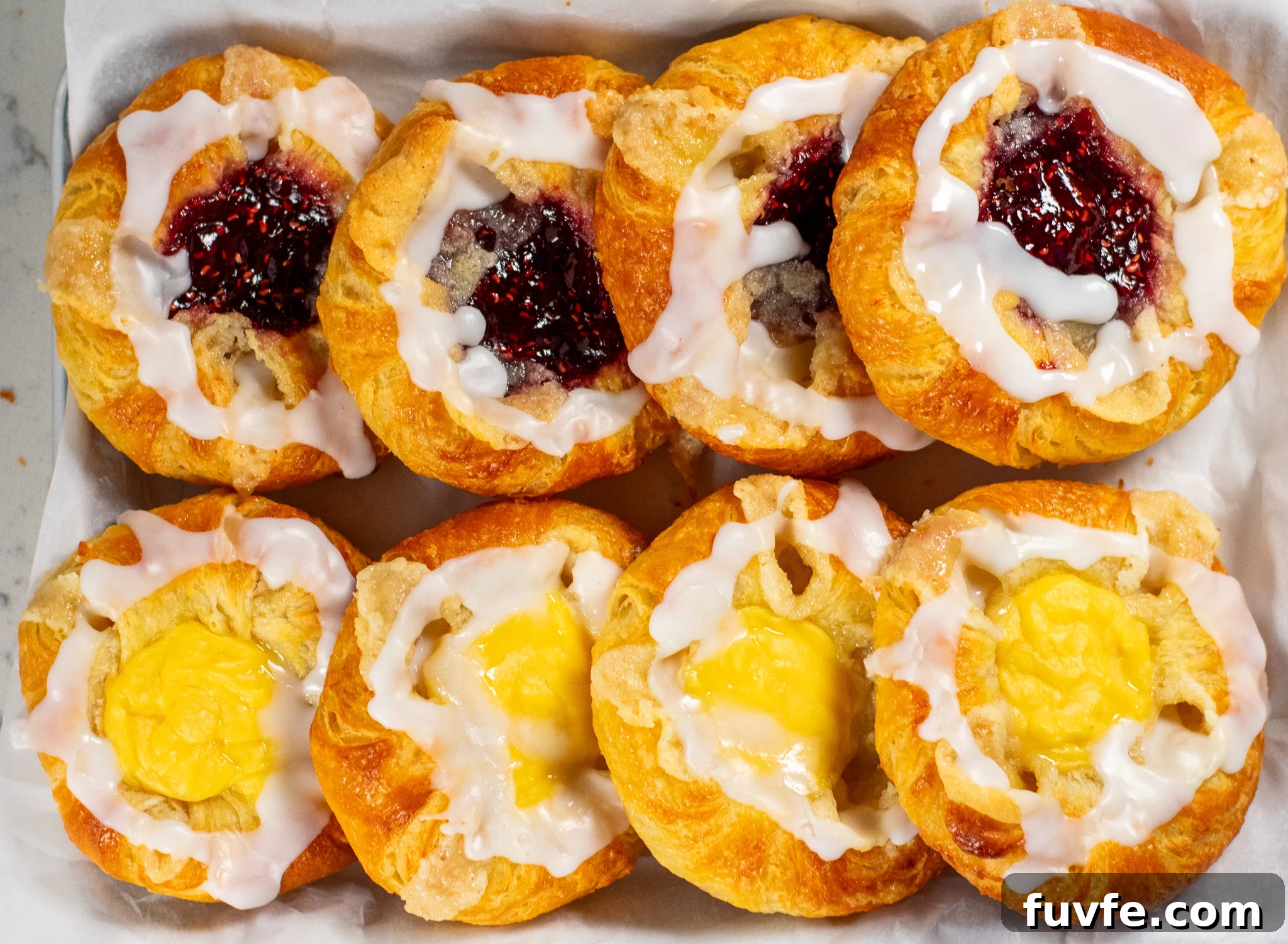 Danish pastries lined up on a baking sheet.