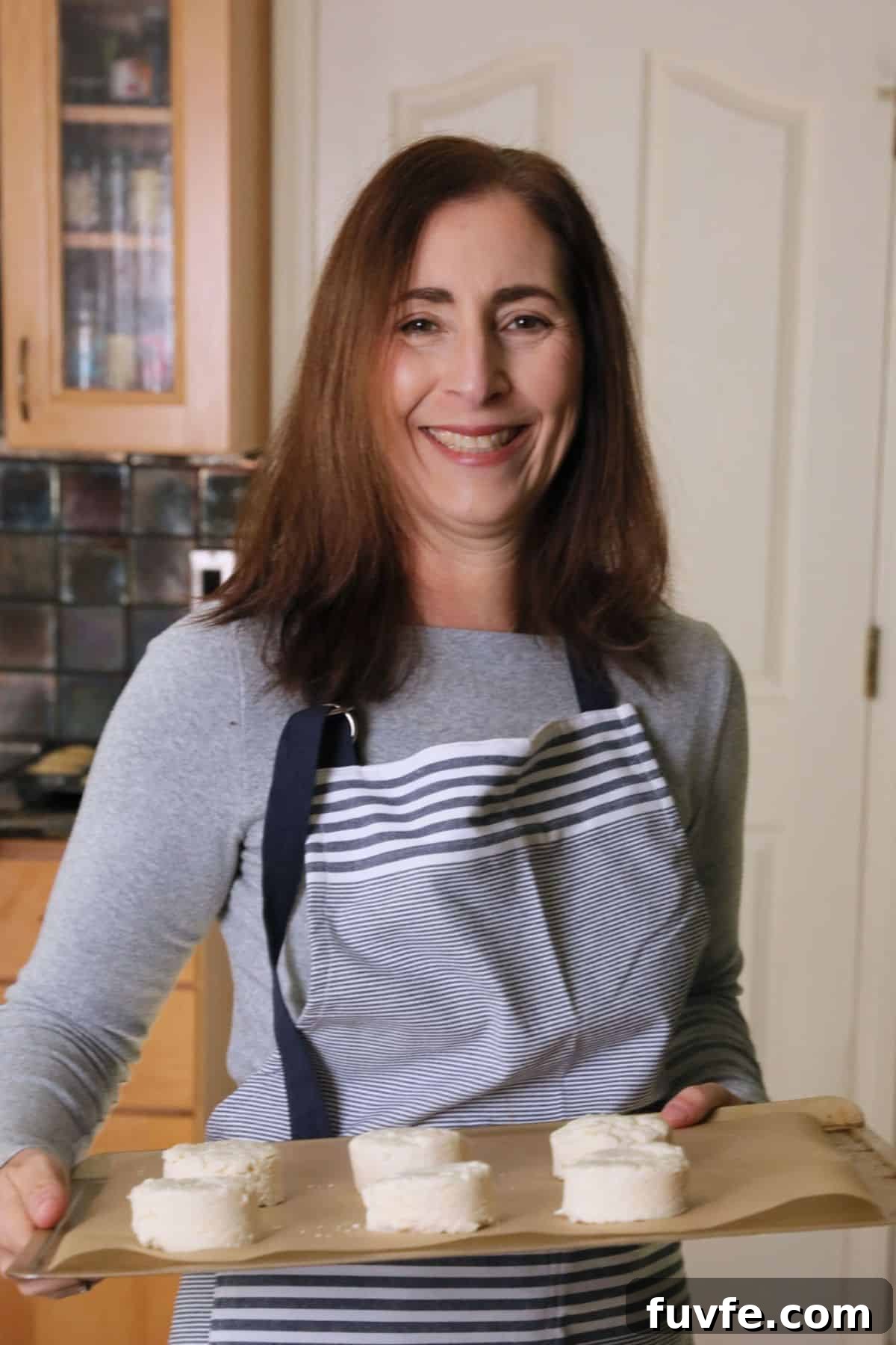 Gluten-Free Pumpkin Sandwich Bread with Cinnamon Swirl 3 Sandi holding a tray of biscuits that are going in the oven to bake.