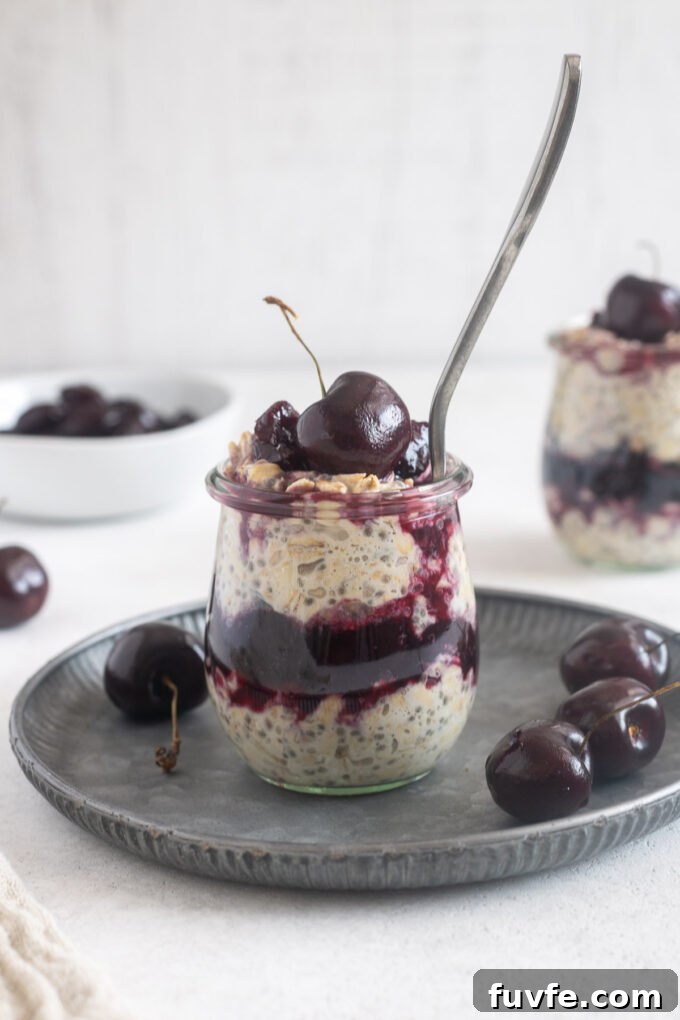 Cherry overnight oats in jars with a spoon digging in.