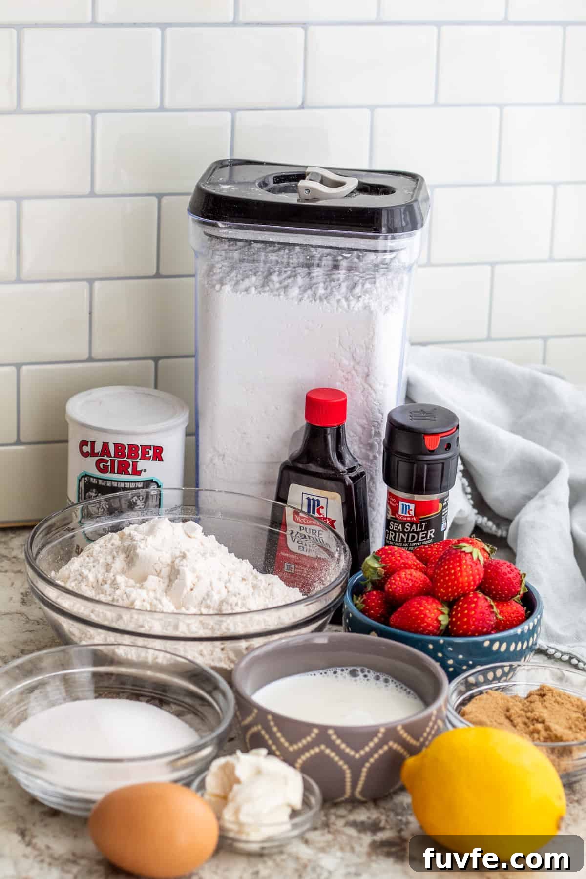 Strawberry loaf cake ingredients laid out on white counter top.