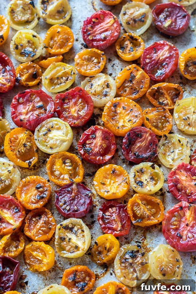 Roasted cherry tomatoes on a baking sheet with basil
