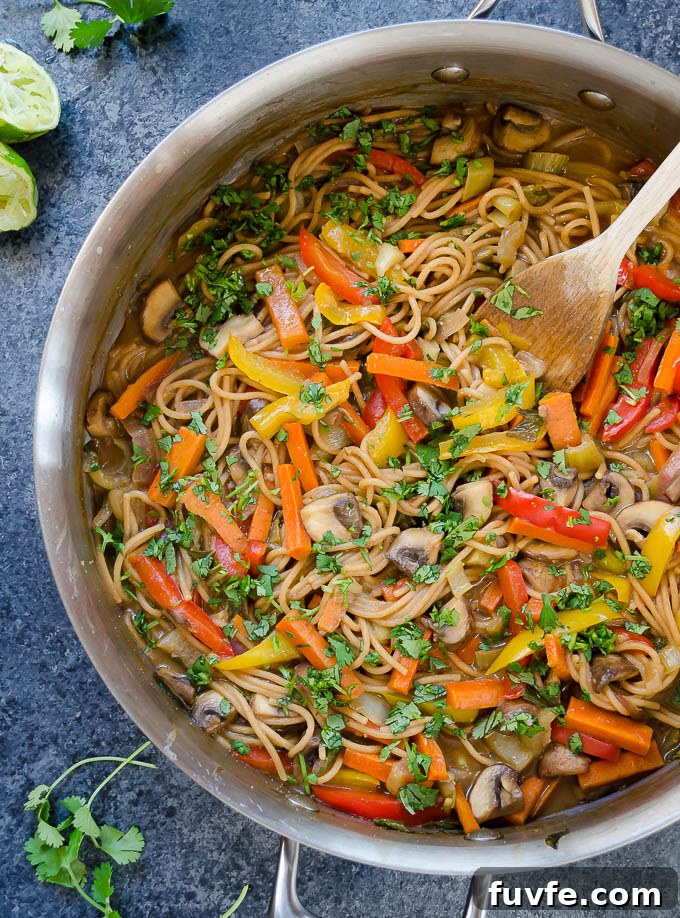 Thai pasta in a skillet with a wooden spoon