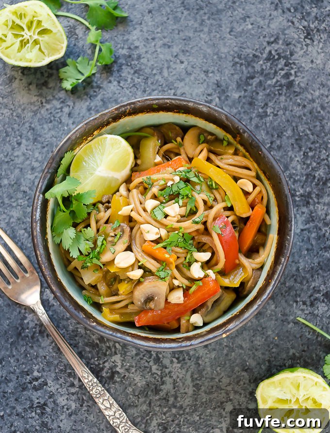 Thai peanut pasta in a bowl with lime and peanuts