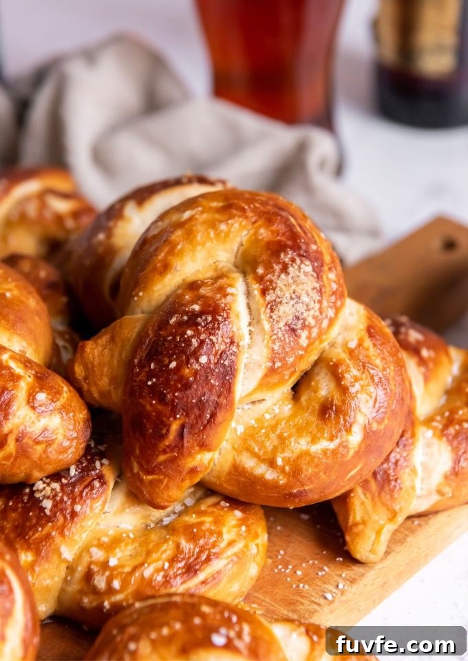 Homemade soft pretzels on a cutting board with a glass of beer