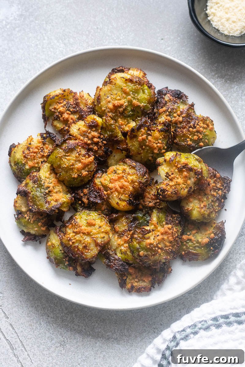 Smashed brussels sprouts on a plate with a serving spoon.