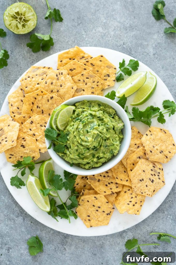 Homemade guacamole on platter with chips and lime