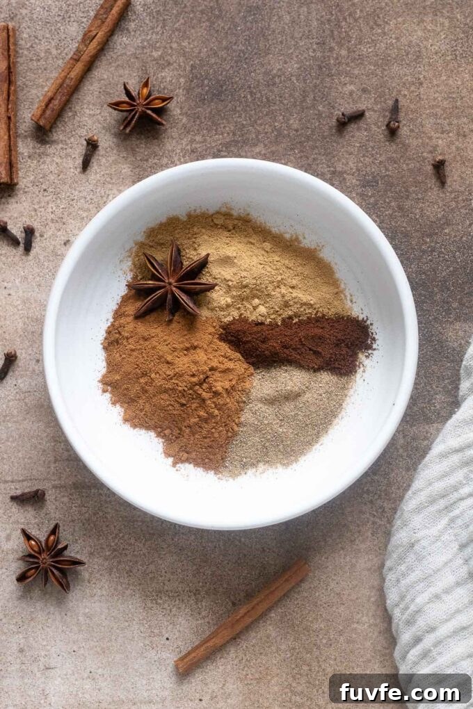 Spices for chai spice mix in a small white bowl.