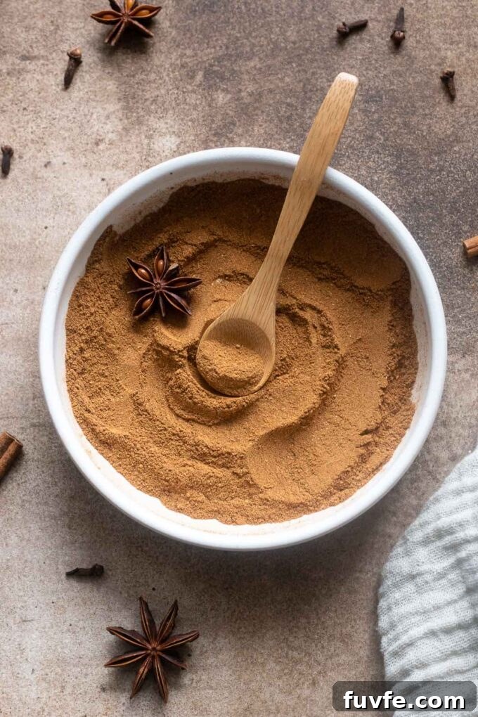 Chai spice blend in a bowl with a spoon buried in the middle.