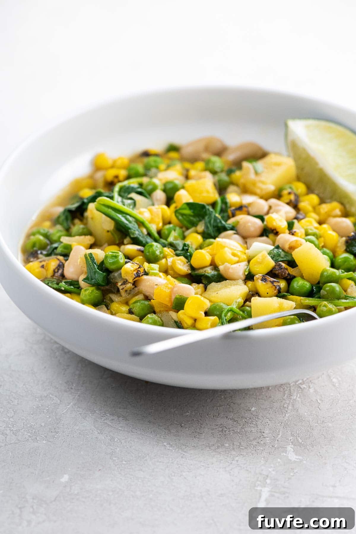 Hearty White Bean Stew with Potatoes and Sweet Corn 2 white bean stew with potatoes and corn in a white bowl with a spoon