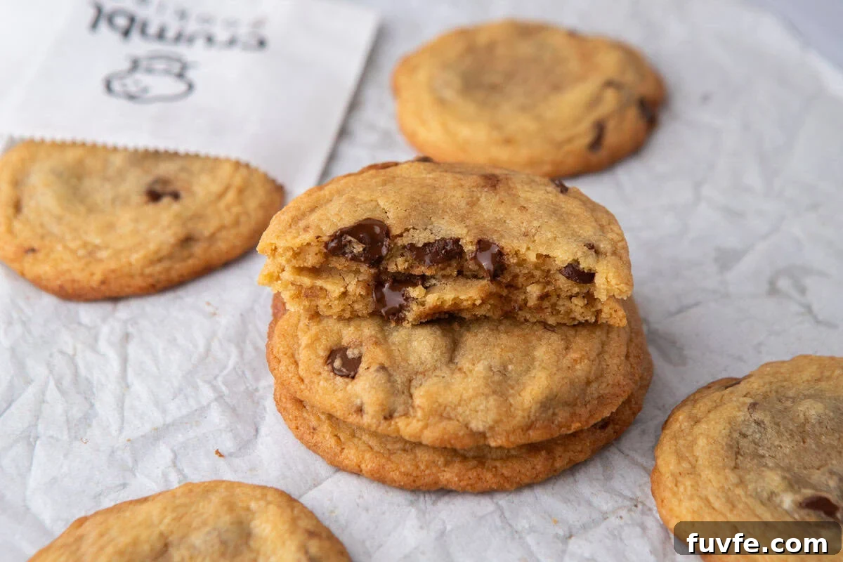 Stack of thin Crumbl-style chocolate chip cookies with melted chocolate centers and crisp golden edges.