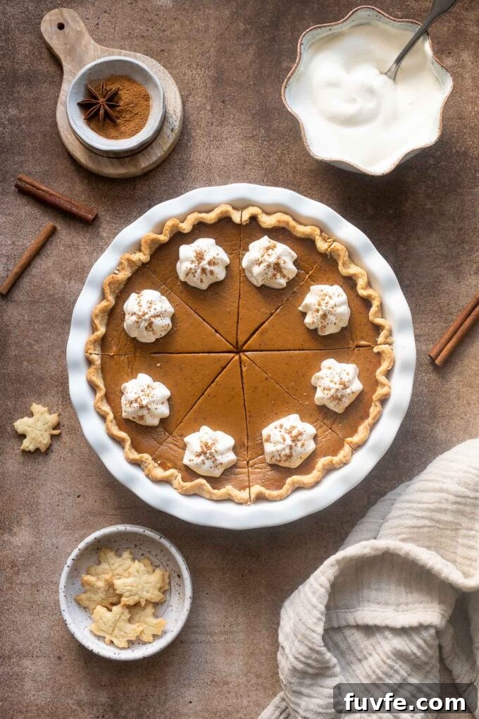 Maple chai pumpkin pie sliced in pie pan with whipped cream.