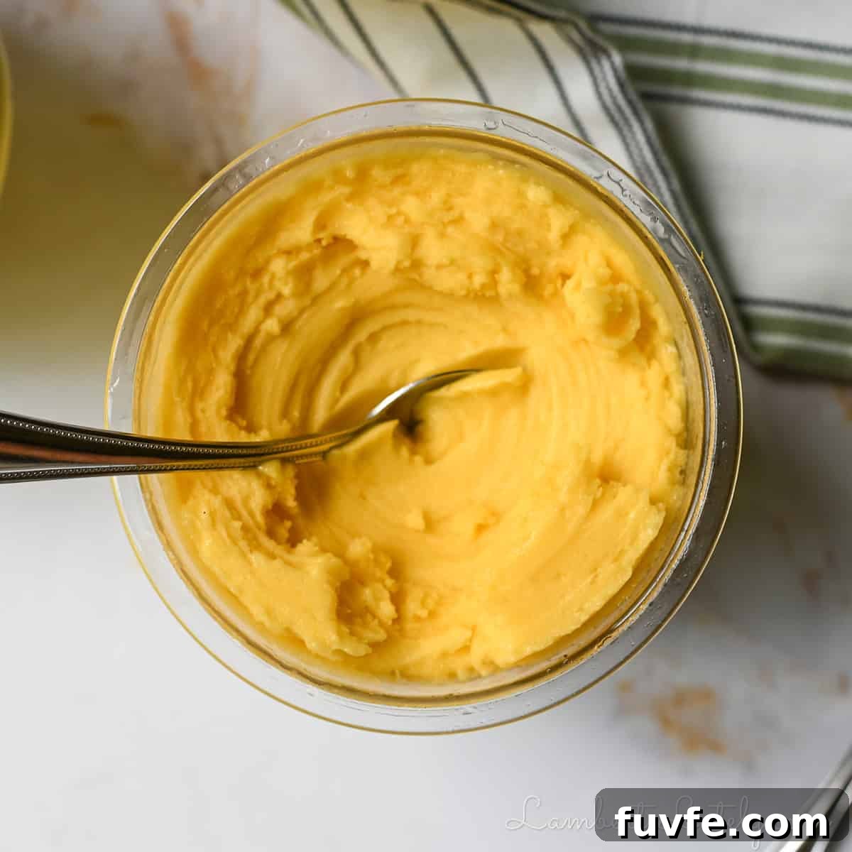 2-Ingredient Mango Sorbet Recipe for Ninja Creami Machines 7 mango sorbet in a Ninja Creami pint container, after spinning, with a spoon in it.