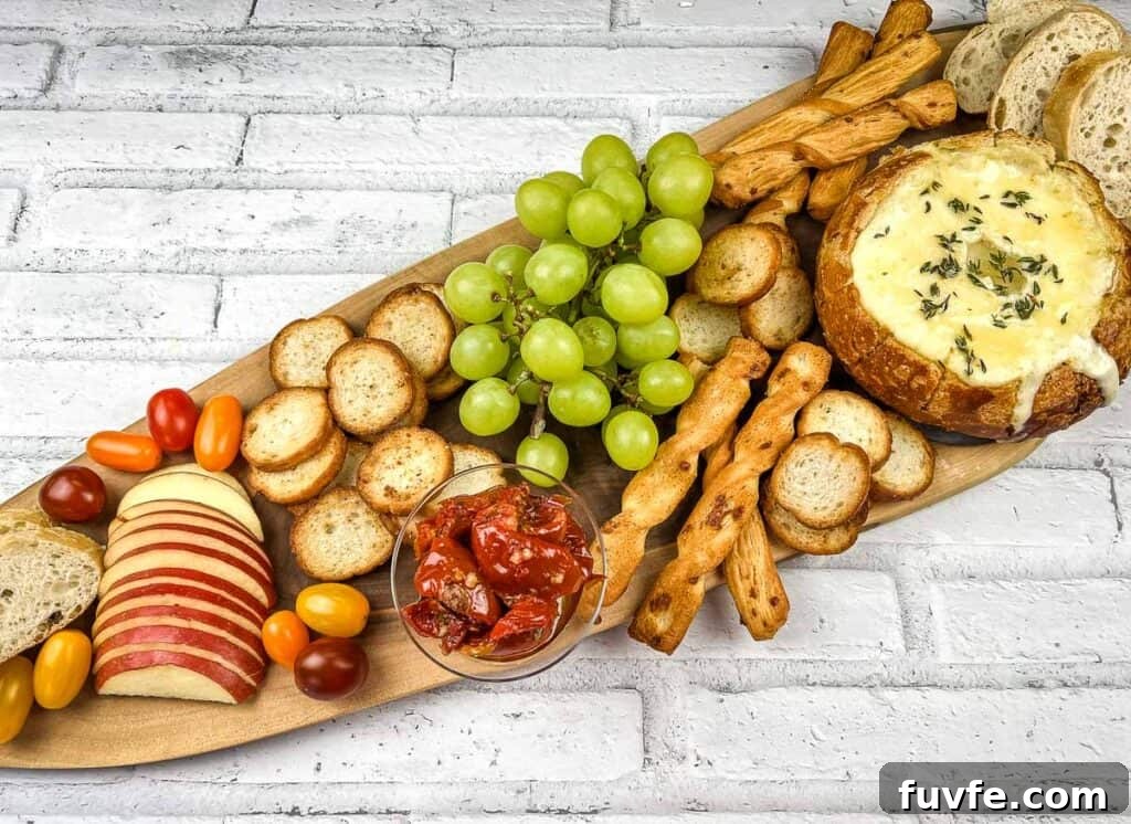 29 Christmas Baking Ideas for Home Bakers Who Love a Busy Oven 27 A wooden platter with baked brie in a bowl, cheese, crackers, grapes and bread.