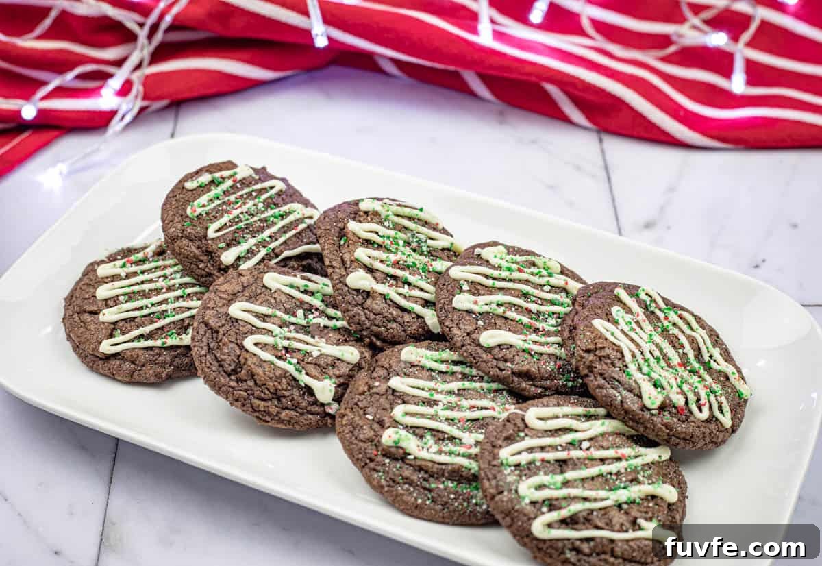 29 Christmas Baking Ideas for Home Bakers Who Love a Busy Oven 28 A plate of chocolate cookies topped with white icing and green sprinkles. A red and white striped cloth is in the background.