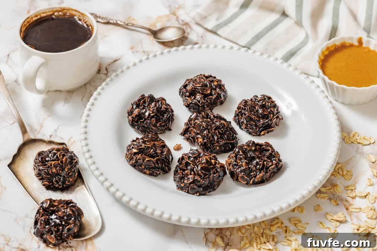 29 Christmas Baking Ideas for Home Bakers Who Love a Busy Oven 4 A white plate with seven Peanut Butter No-Bake Cookies on a marble surface, surrounded by a cup of coffee, a spoon, a bowl of nut butter, oats, and a striped cloth.