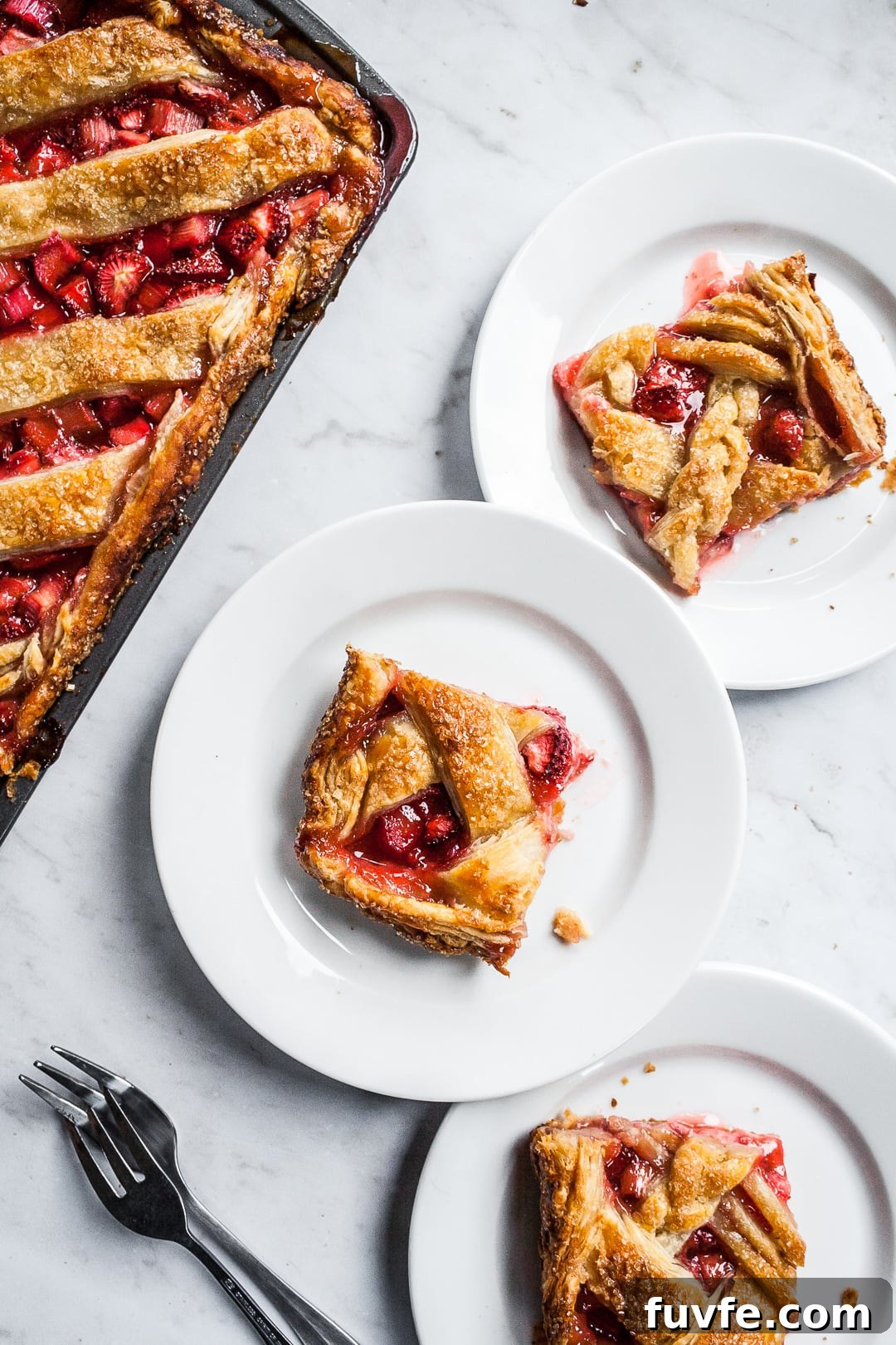 Strawberry Rhubarb Slab Pie Recipe — Perfect for Parties 14 Slices of slab pie on white plates next to a sheet pan of slab pie