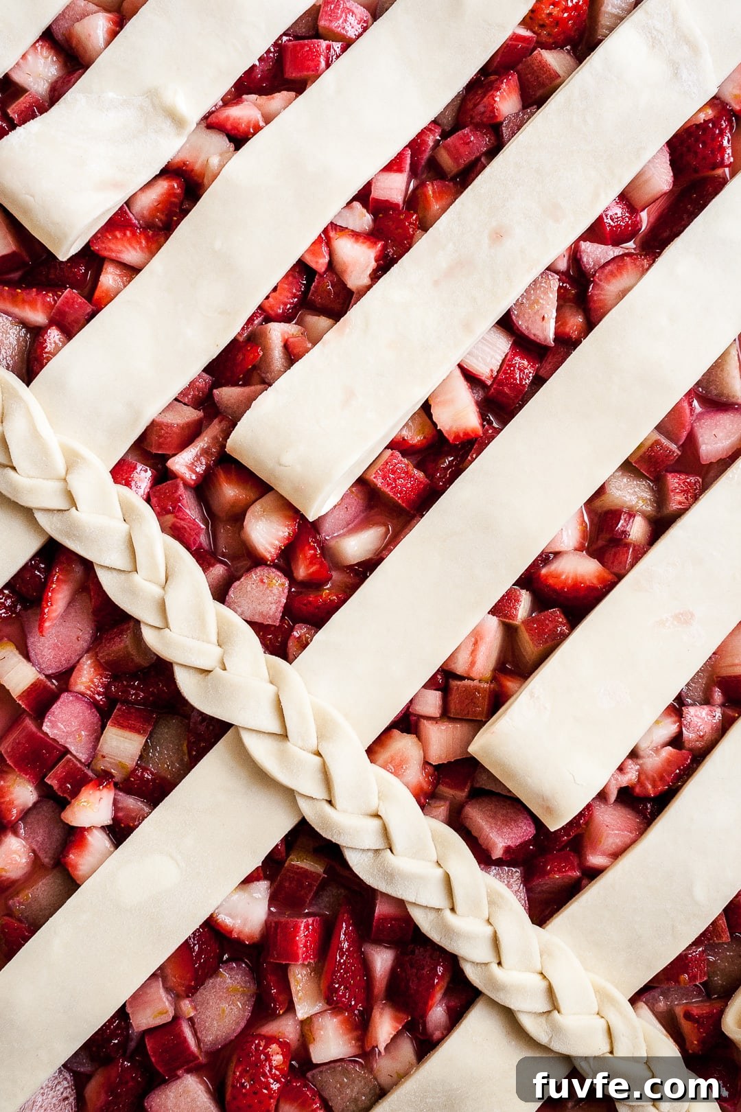 Strawberry Rhubarb Slab Pie Recipe — Perfect for Parties 3 Close up of strawberry rhubarb pie filling with lattice dough strips and braid angled on top