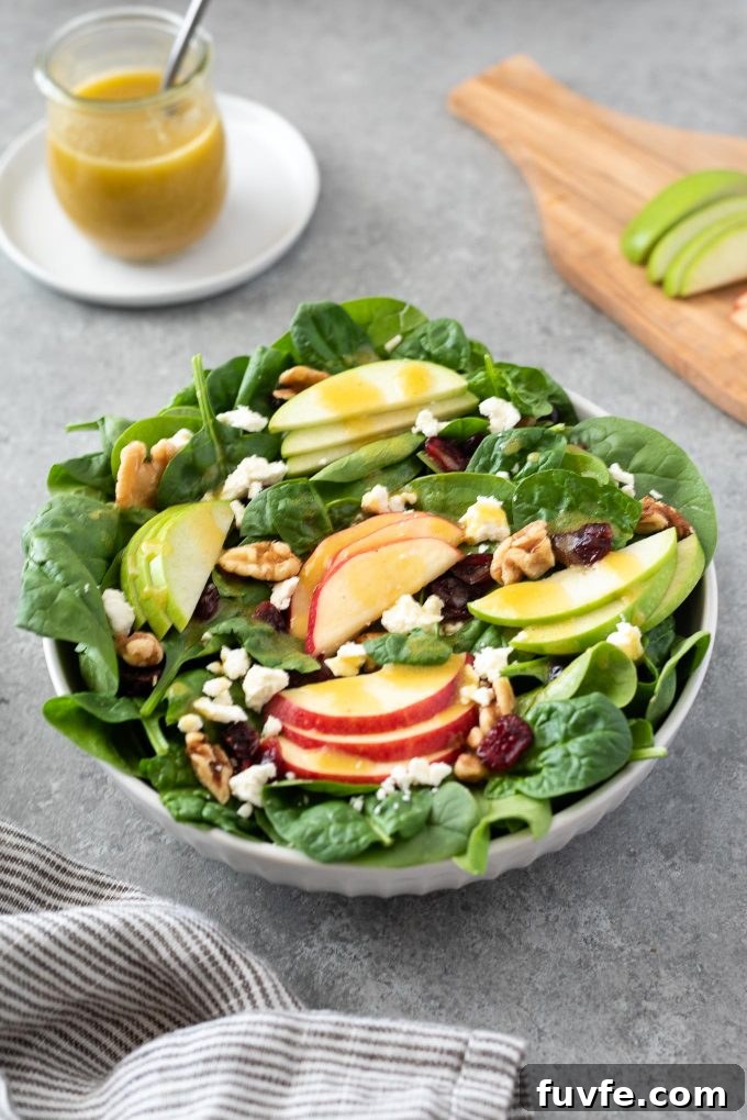 Crisp Spinach and Apple Salad with Feta and Walnuts 2 Spinach Apple Salad in a bowl with dressing in background