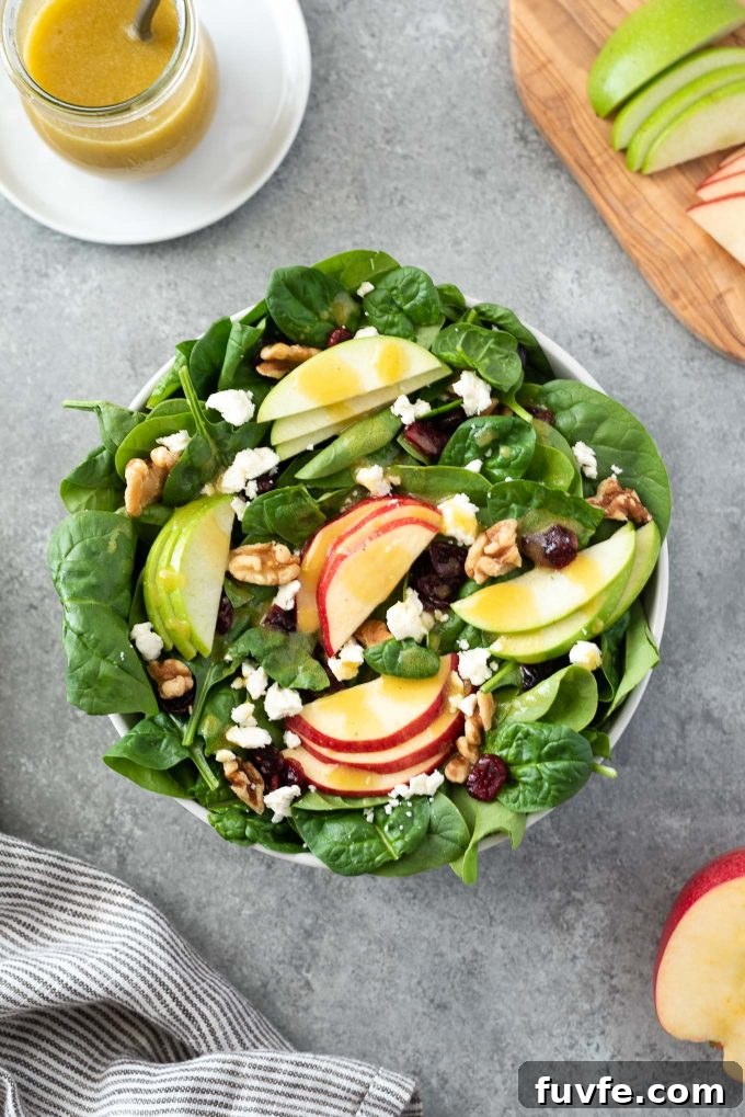 Crisp Spinach and Apple Salad with Feta and Walnuts 5 Spinach and apple salad in a bowl with dressing behind