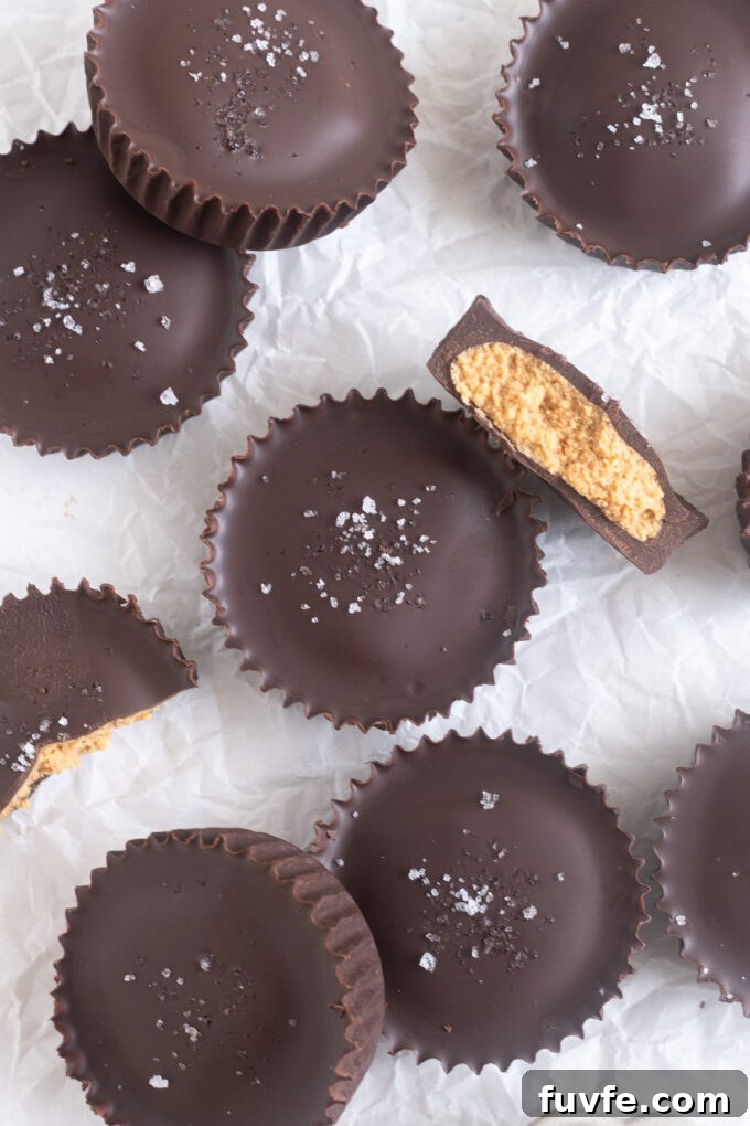 Overhead shot of homemade protein peanut butter cups topped with flaky sea salt on parchment paper.