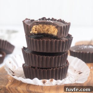 Stack of protein peanut butter cups on a cutting board with flaky sea salt scattered around.