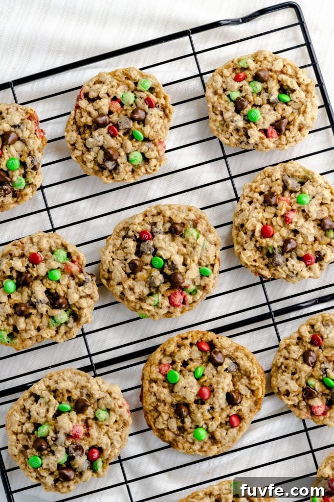 Chocolate chip oatmeal cookies with red and green M&M's on black cooling rack.