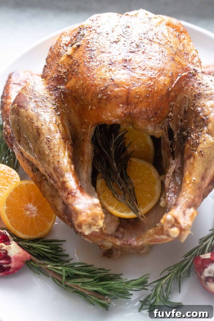 Orange rosemary roast turkey on a platter stuffed with orange and rosemary.