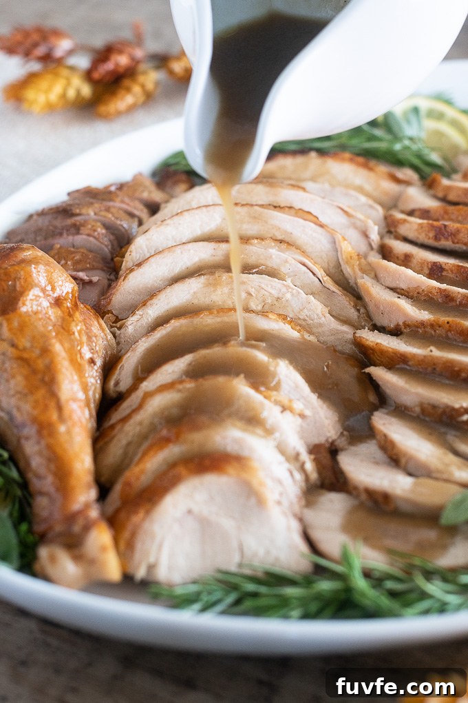 roast turkey sliced on a platter with gravy pouring