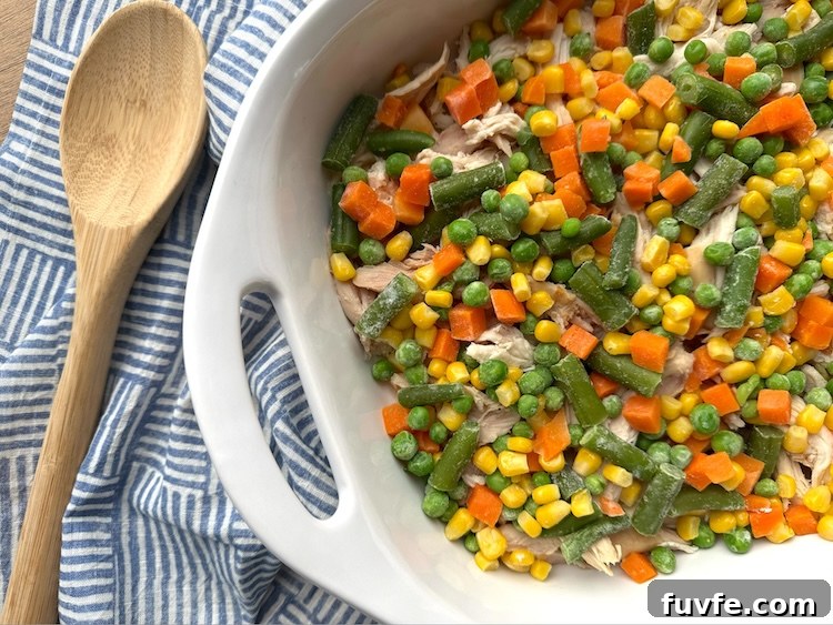 Frozen mixed vegetables in a casserole dish to make a popular chicken cobbler for dinner.