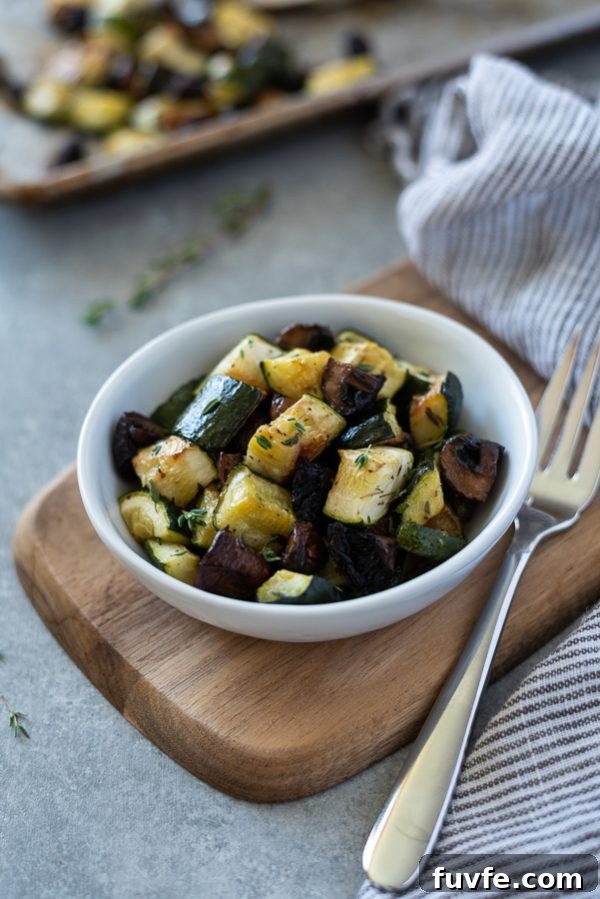 Garlic-Roasted Zucchini and Mushrooms Recipe 2 Roasted zucchini and mushrooms in a white bowl with a fork