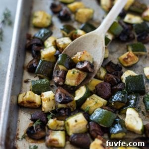 Garlic-Roasted Zucchini and Mushrooms Recipe 7 Roasted zucchini and mushrooms on a sheet pan with a wooden spoon