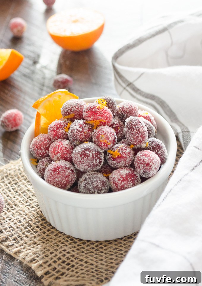 Sparkling Orange Sugared Cranberries Recipe 7 Candied cranberries in a white ramekin with orange slice